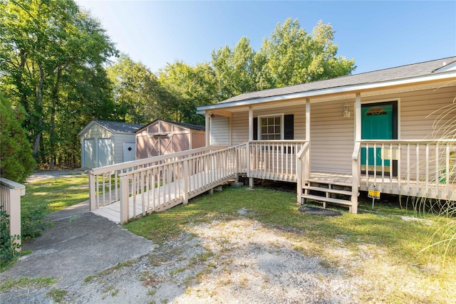 view of front of home featuring covered porch, a front yard, and a storage unit