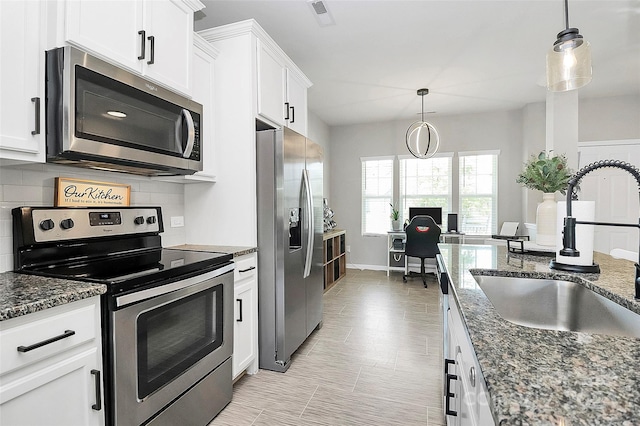 kitchen featuring dark stone countertops, appliances with stainless steel finishes, white cabinetry, and sink