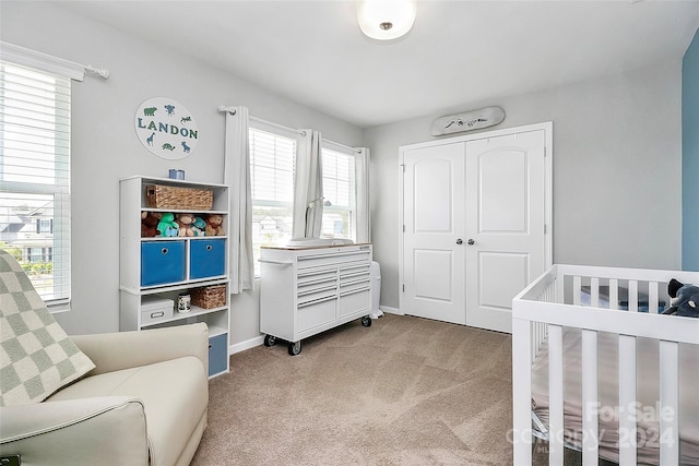 bedroom with a closet, light colored carpet, and a crib