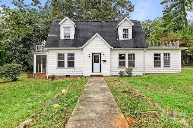 cape cod-style house featuring a balcony and a front lawn