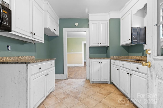 kitchen with white cabinets, light tile patterned floors, crown molding, and dark stone countertops