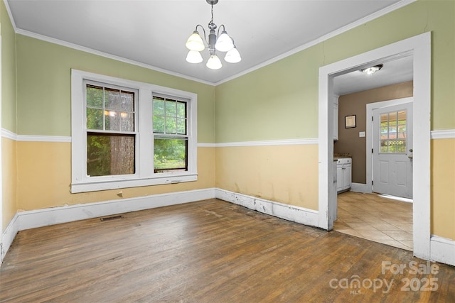 unfurnished room featuring hardwood / wood-style flooring, an inviting chandelier, and ornamental molding