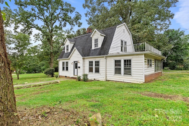 view of front of home with a balcony and a front yard