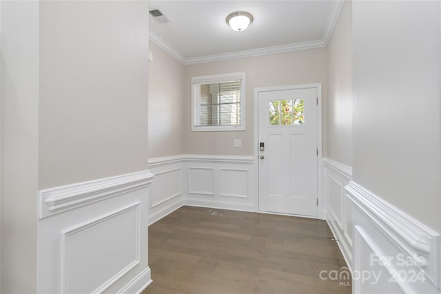 doorway featuring ornamental molding, a wainscoted wall, dark wood-type flooring, and visible vents