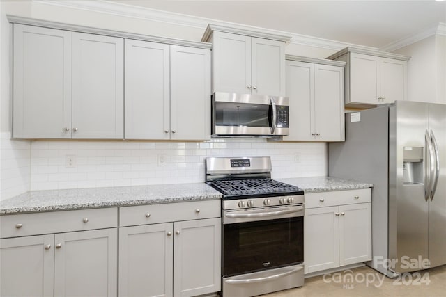 kitchen featuring ornamental molding, appliances with stainless steel finishes, light stone counters, and tasteful backsplash