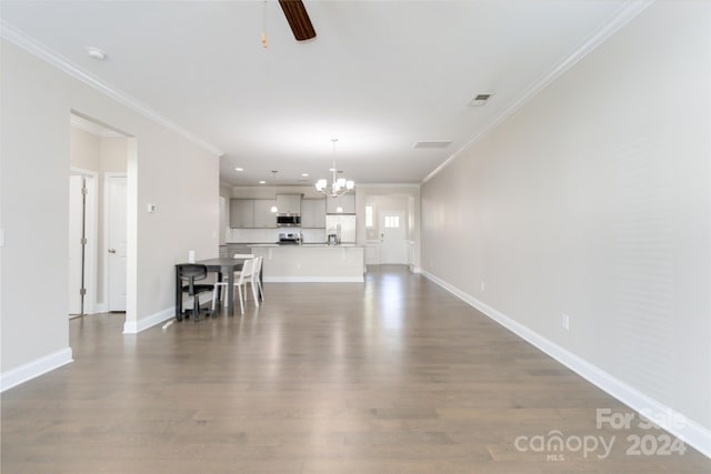 unfurnished living room featuring baseboards, dark wood finished floors, crown molding, and ceiling fan with notable chandelier