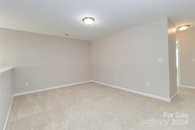 unfurnished room with baseboards, visible vents, and light colored carpet