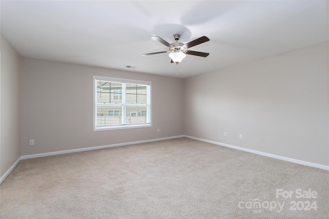 unfurnished room featuring baseboards, visible vents, a ceiling fan, and light colored carpet