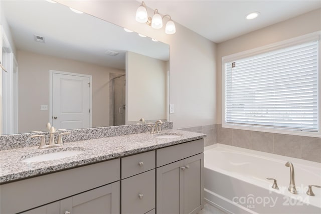 bathroom featuring a garden tub, double vanity, a sink, and visible vents