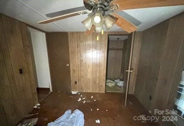 interior space featuring wood walls and ceiling fan