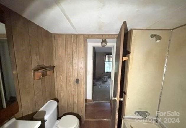 bathroom with wood walls and toilet