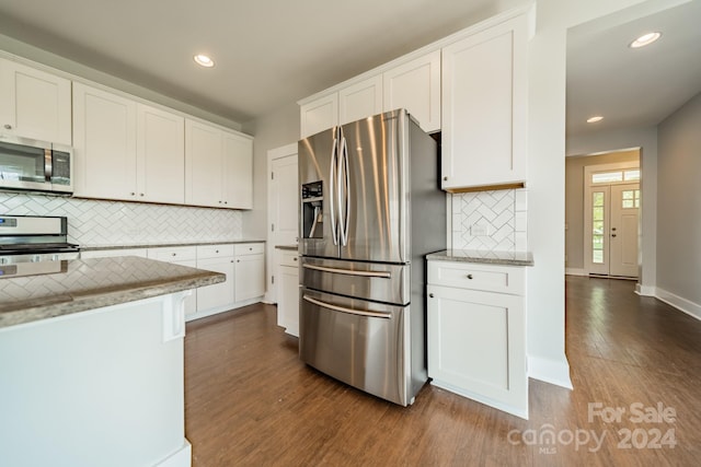 kitchen with appliances with stainless steel finishes, dark hardwood / wood-style flooring, backsplash, and white cabinets