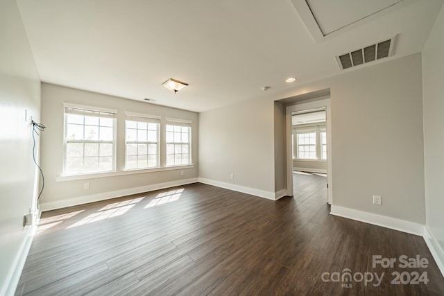 empty room with dark hardwood / wood-style floors and a healthy amount of sunlight