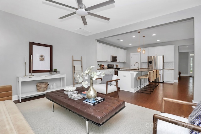 living room with ceiling fan, sink, and dark hardwood / wood-style flooring