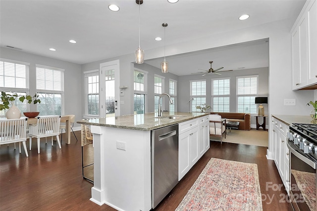 kitchen featuring sink, stainless steel appliances, an island with sink, white cabinets, and decorative light fixtures