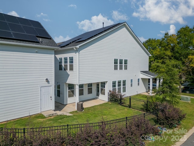 rear view of property with a patio, a lawn, and solar panels