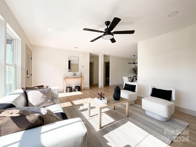 living room with ceiling fan with notable chandelier and light wood-type flooring