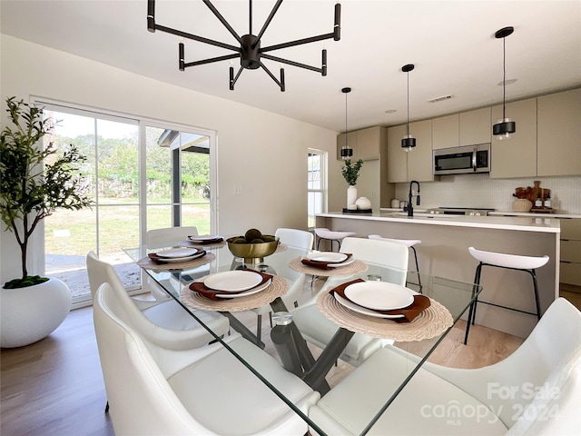 dining area with light hardwood / wood-style flooring, an inviting chandelier, and sink