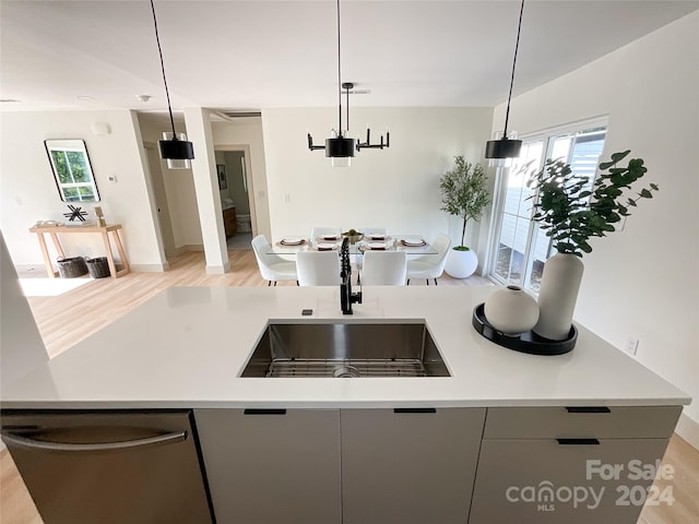 kitchen featuring gray cabinetry, light hardwood / wood-style floors, pendant lighting, stainless steel dishwasher, and sink