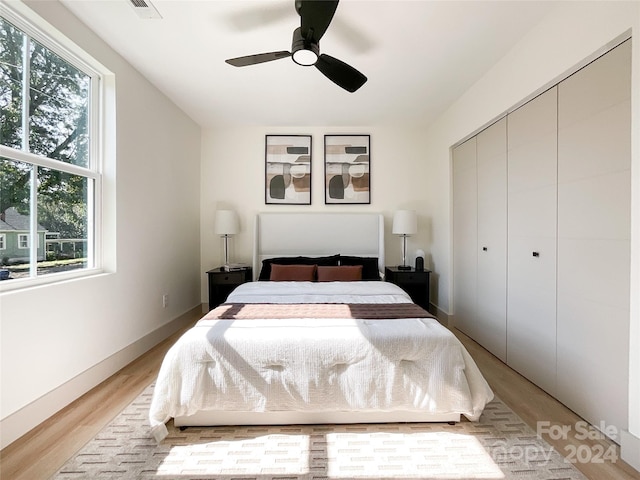 bedroom with ceiling fan, light hardwood / wood-style flooring, and a closet