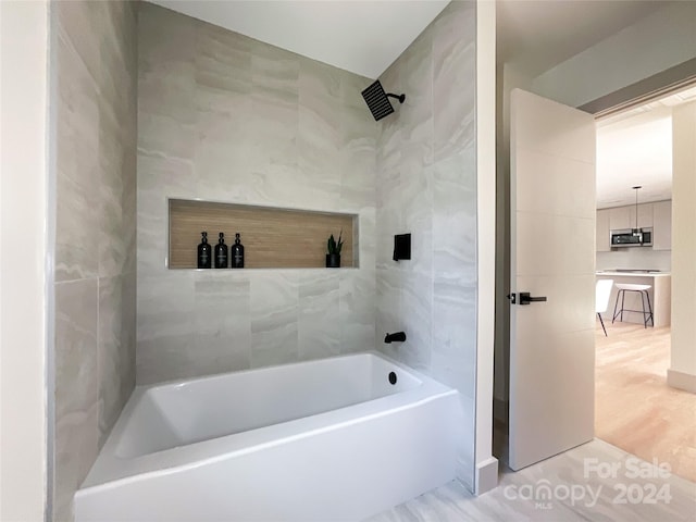 bathroom featuring tile walls, hardwood / wood-style floors, and tiled shower / bath