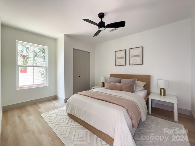 bedroom with ceiling fan, light hardwood / wood-style flooring, and a closet