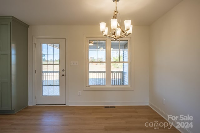 doorway to outside with an inviting chandelier and light hardwood / wood-style floors