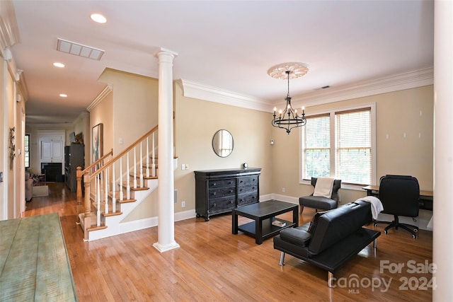 living room featuring a notable chandelier, crown molding, light hardwood / wood-style flooring, and ornate columns