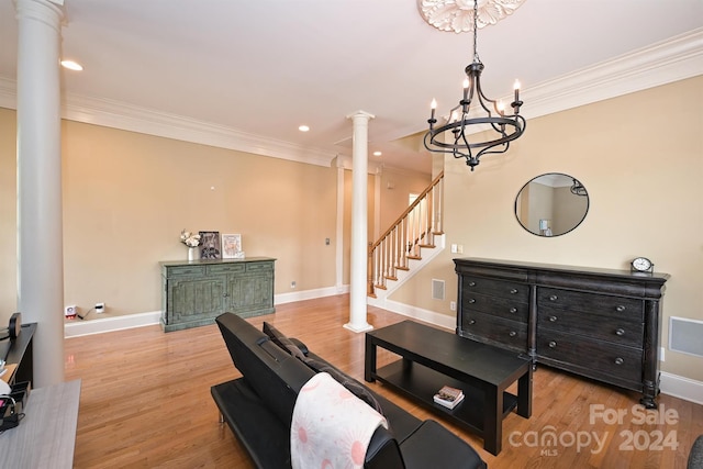 interior space with ornamental molding, an inviting chandelier, light hardwood / wood-style flooring, and decorative columns