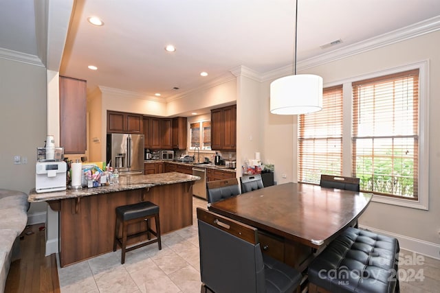 kitchen featuring decorative light fixtures, appliances with stainless steel finishes, plenty of natural light, and crown molding