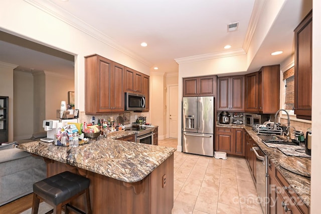 kitchen featuring tasteful backsplash, a breakfast bar area, kitchen peninsula, stone counters, and stainless steel appliances