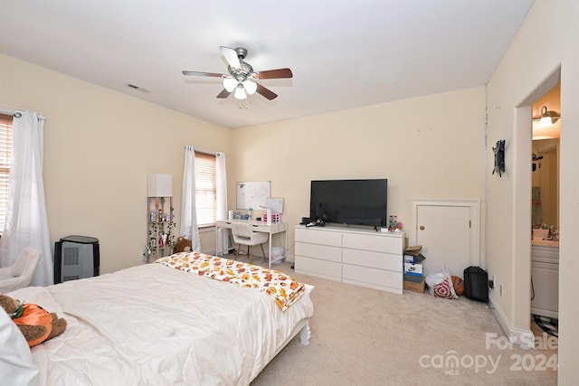 bedroom with light carpet, ensuite bath, and ceiling fan