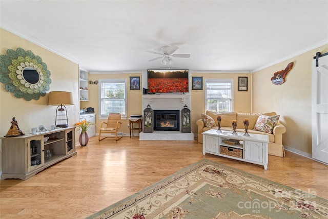 living room featuring light wood-type flooring, ceiling fan, crown molding, and a healthy amount of sunlight