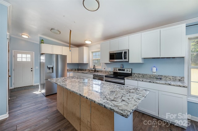 kitchen featuring white cabinetry, a center island, light stone counters, lofted ceiling, and appliances with stainless steel finishes