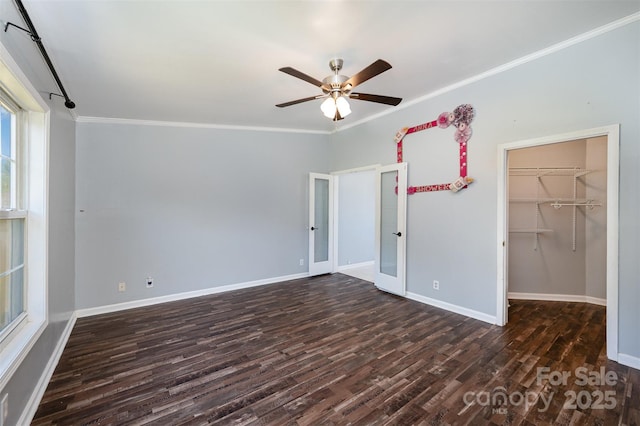 unfurnished bedroom featuring dark hardwood / wood-style flooring, ceiling fan, crown molding, a spacious closet, and a closet