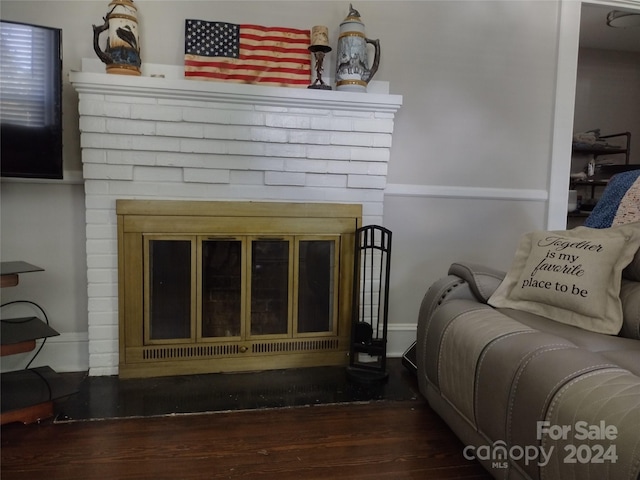 living room featuring dark hardwood / wood-style flooring and a brick fireplace