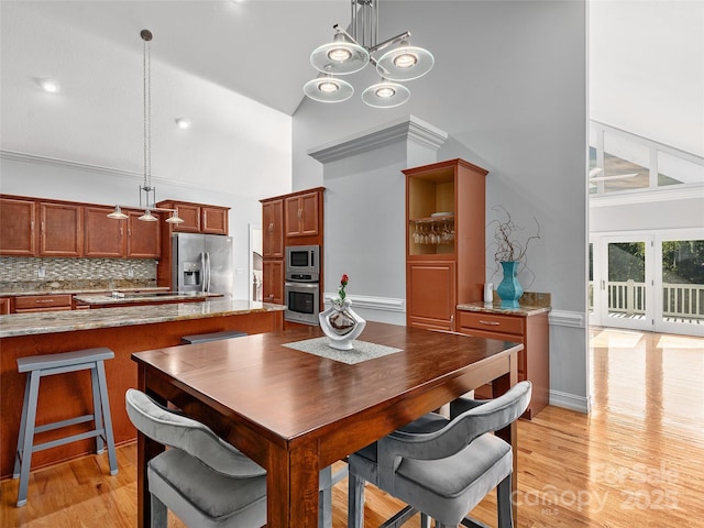 dining space featuring high vaulted ceiling, french doors, and light hardwood / wood-style floors