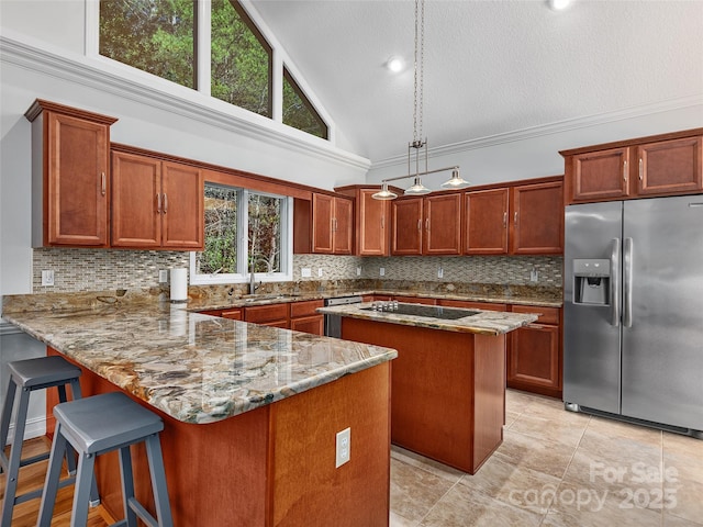 kitchen featuring pendant lighting, kitchen peninsula, stainless steel appliances, high vaulted ceiling, and light stone counters