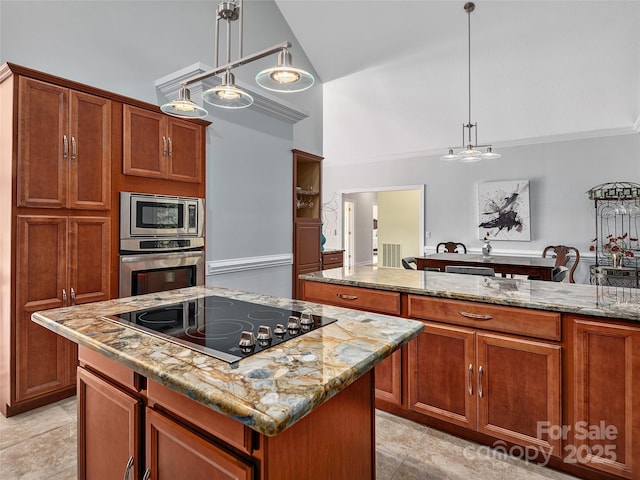 kitchen featuring appliances with stainless steel finishes, decorative light fixtures, vaulted ceiling, light stone counters, and a center island