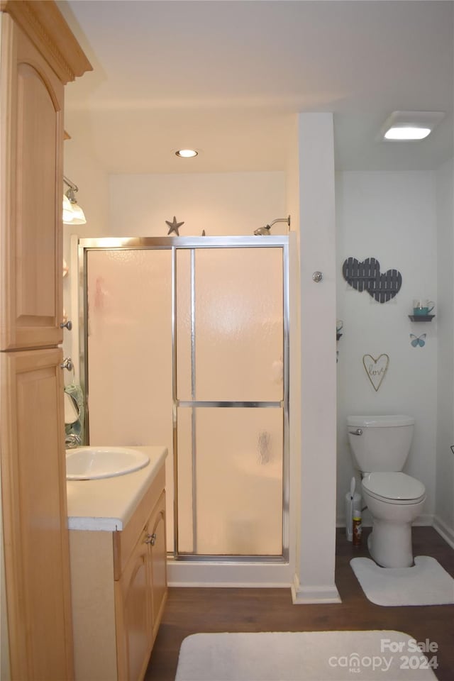 bathroom featuring hardwood / wood-style floors, walk in shower, toilet, and vanity