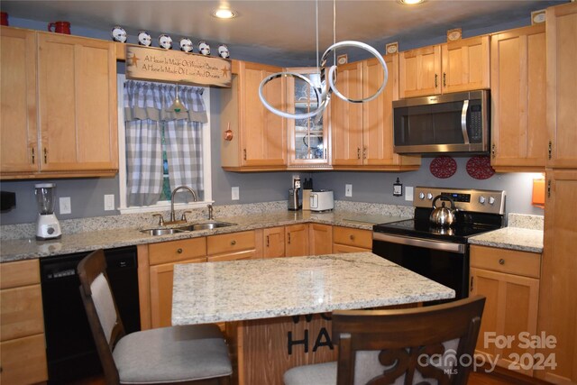 kitchen with light stone countertops, a kitchen bar, stainless steel appliances, and sink