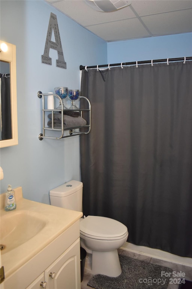 bathroom featuring walk in shower, toilet, a drop ceiling, and vanity