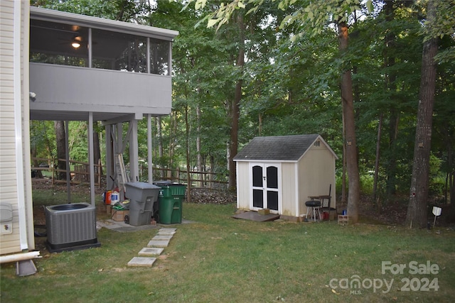 view of yard featuring central air condition unit, a storage shed, and a sunroom