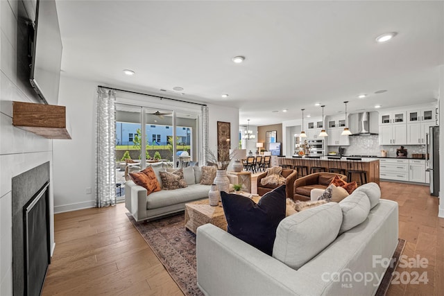 living room featuring an inviting chandelier, light hardwood / wood-style floors, and a tile fireplace