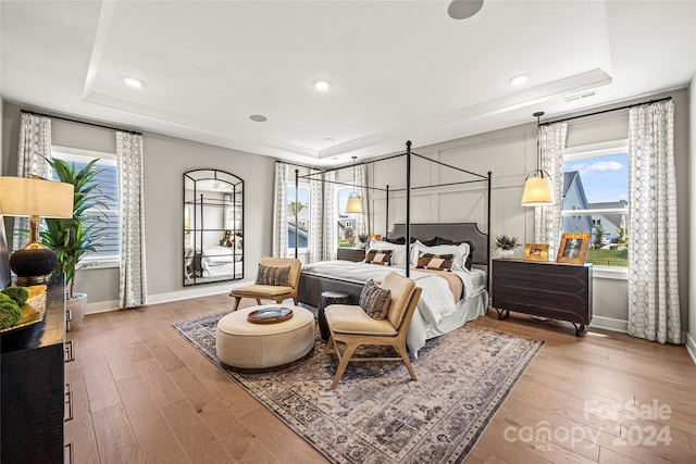 bedroom with wood-type flooring and a tray ceiling