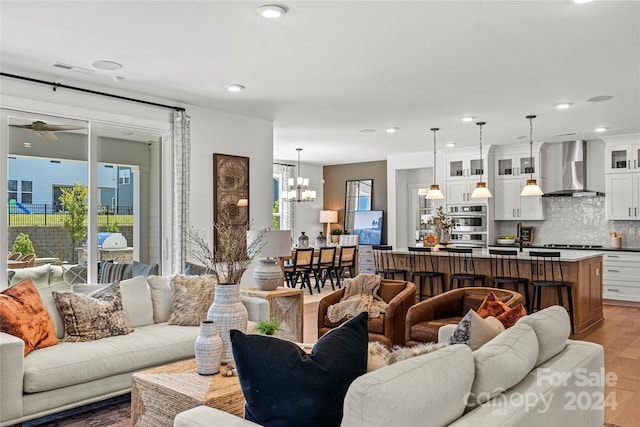 living room with ceiling fan with notable chandelier and hardwood / wood-style floors