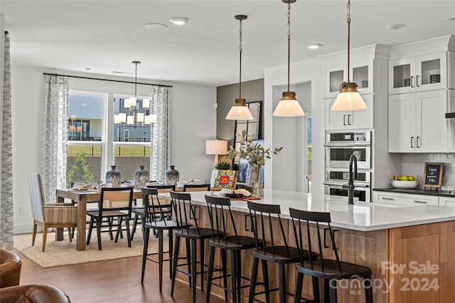 kitchen featuring pendant lighting, white cabinetry, dark hardwood / wood-style flooring, double oven, and a spacious island