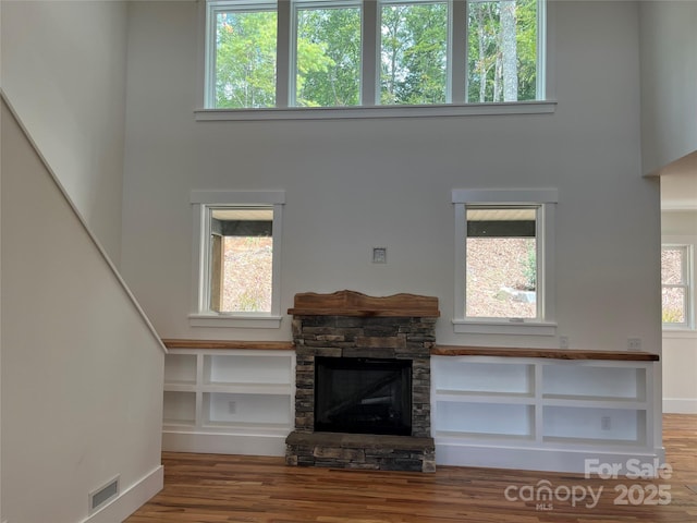 unfurnished living room with a fireplace, wood-type flooring, and a high ceiling