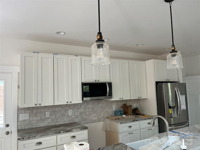 kitchen with white cabinetry, hanging light fixtures, appliances with stainless steel finishes, and tasteful backsplash