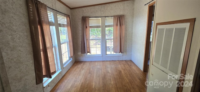 interior space featuring ornamental molding, multiple windows, and light wood-type flooring